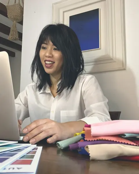 Valentina al computer durante una consulenza online, con tessuti colorati sul tavolo