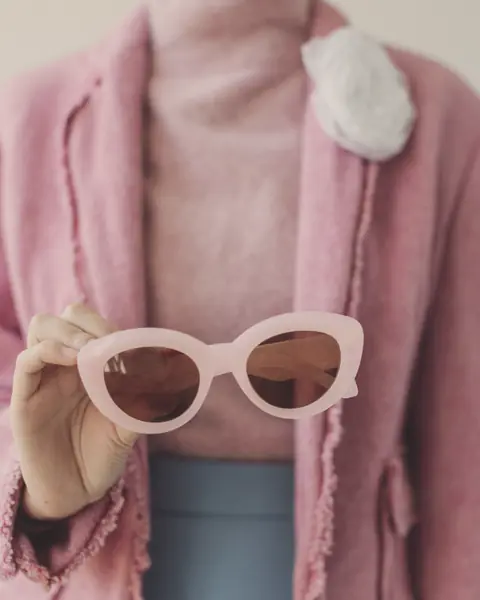 Dettaglio di un outfit rosa con occhiali da sole